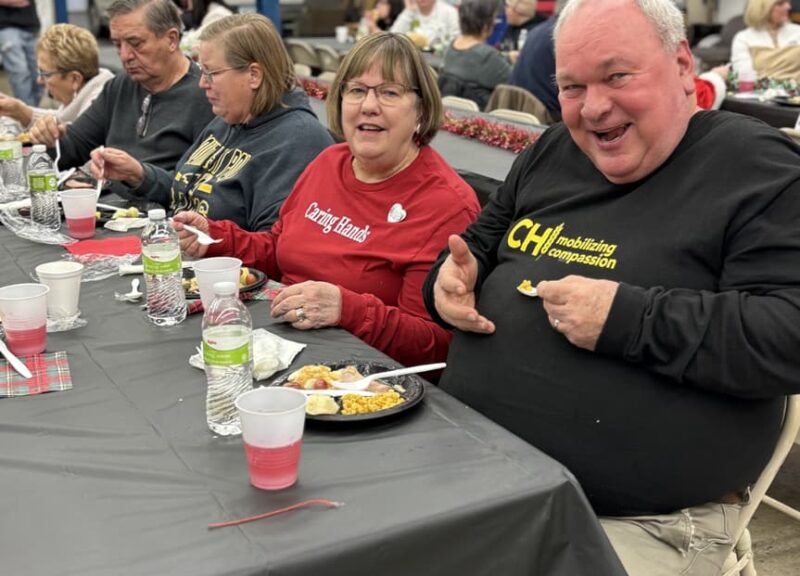 ae3c99_0de84c871142476cbddca193da354833~mv2-min people sitting at table eating