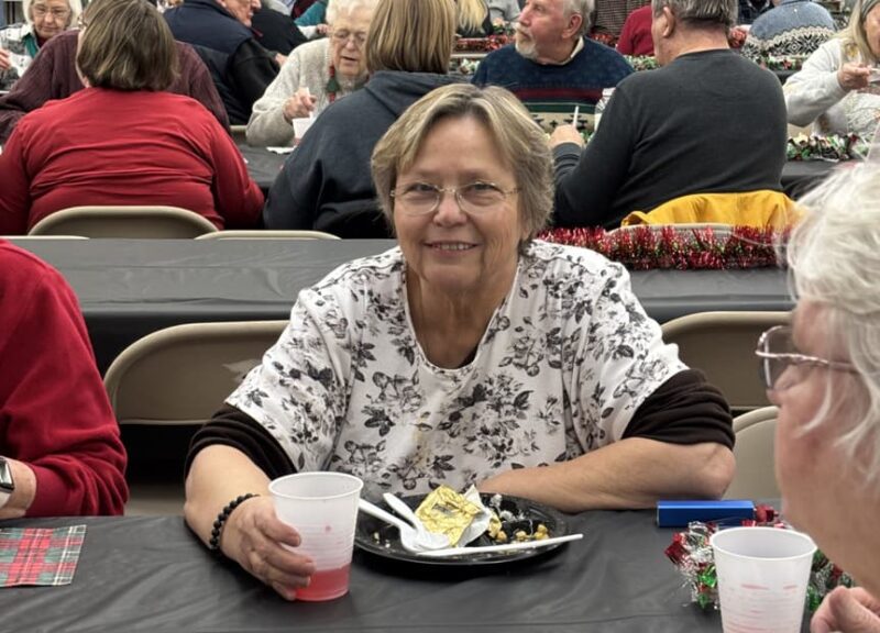ae3c99_15c248608c574ddba0fa190c0d3a9b4d~mv2-min person sitting at table eating with many people in background