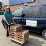Person pushing flat of strawberries in front of a van