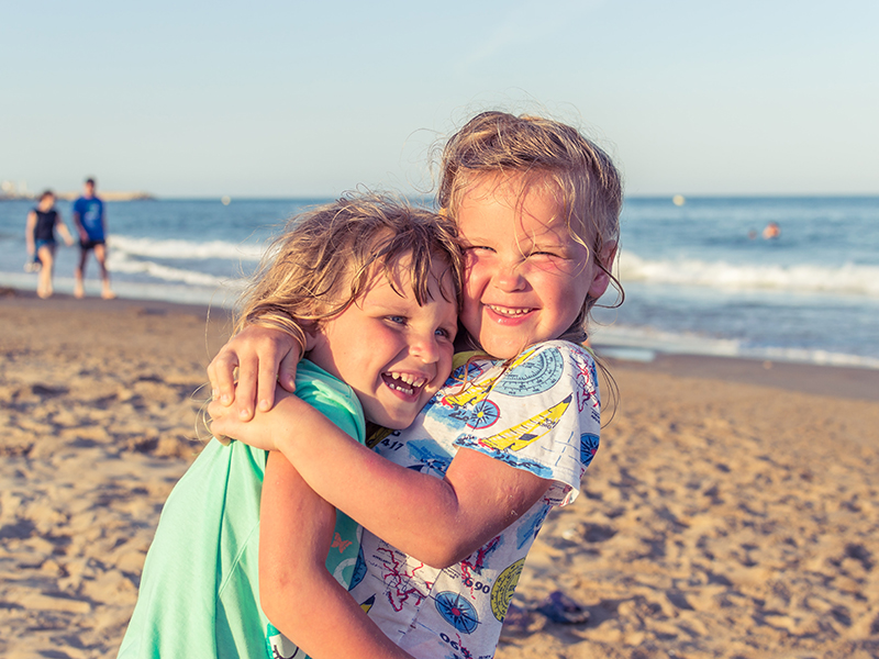 two young girls hugging on the beach