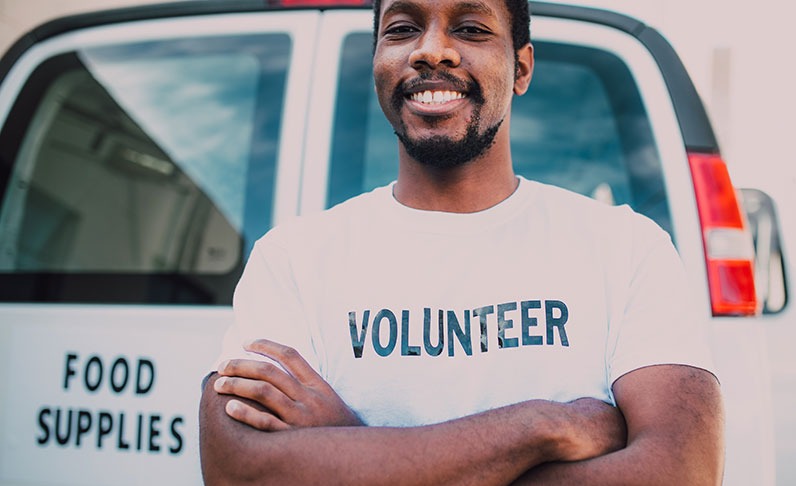 Volunteer crossing arms in front of van of food supplies