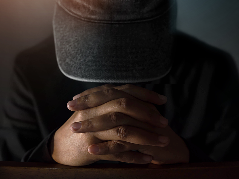 Person praying head down hands together